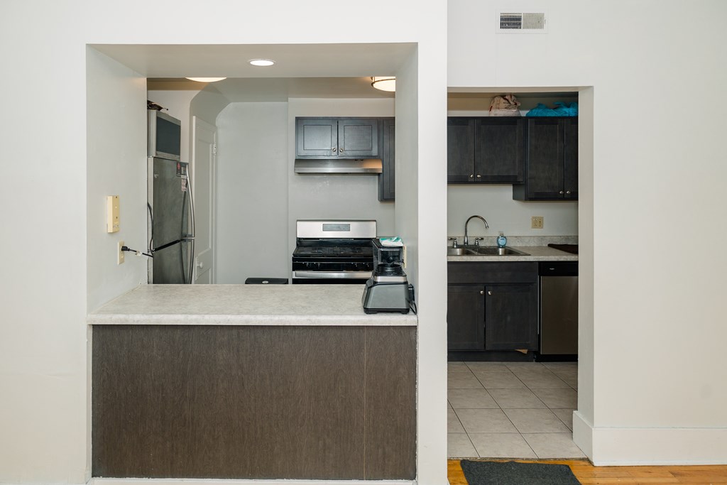 A kitchen with a refrigerator, microwave, oven, and sink.