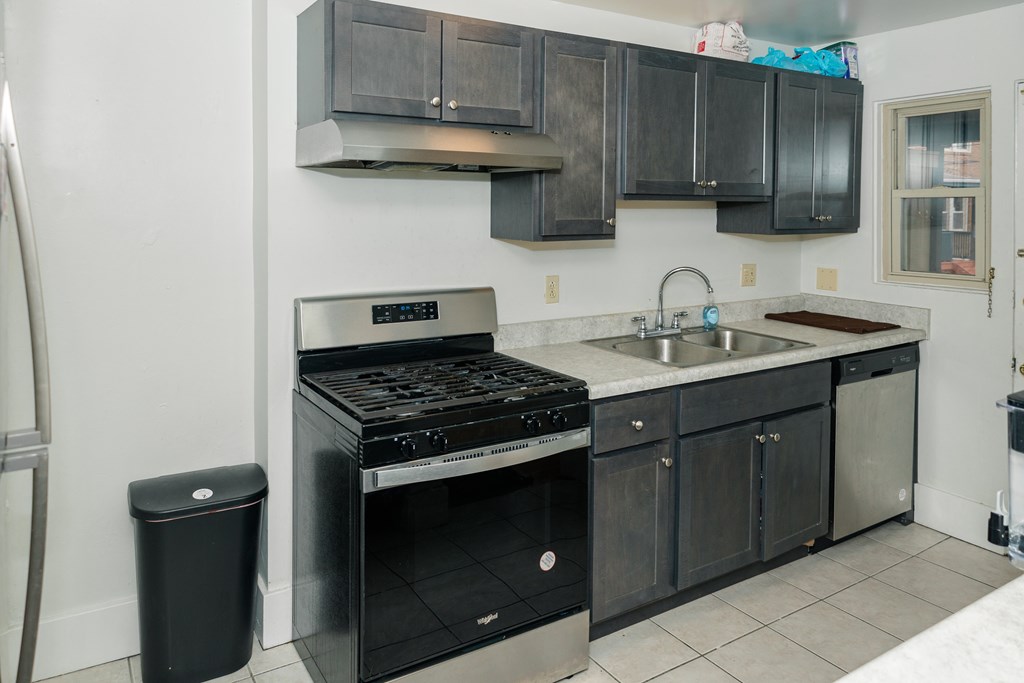 A kitchen with black cabinets and a stainless steel oven.