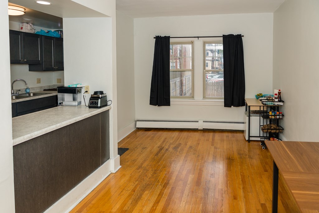 A kitchen with black cabinets and a wooden floor.