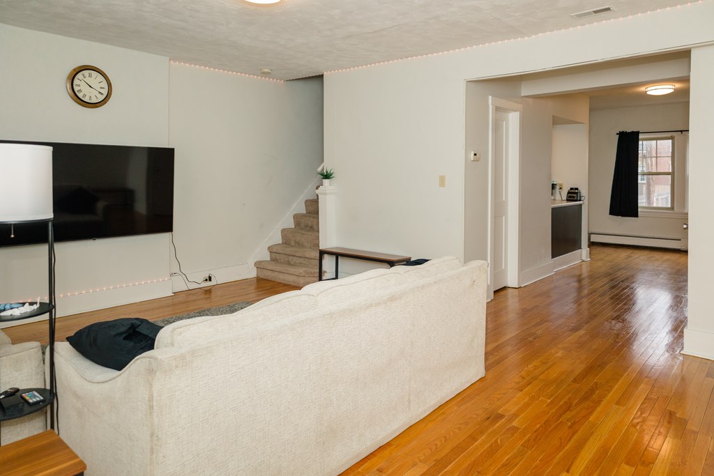 A living room with a couch, television, and stairs.