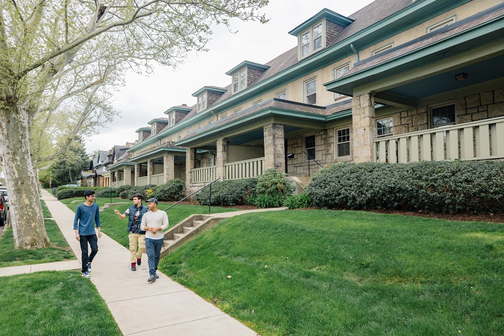 Three men walking on a sidewalk.