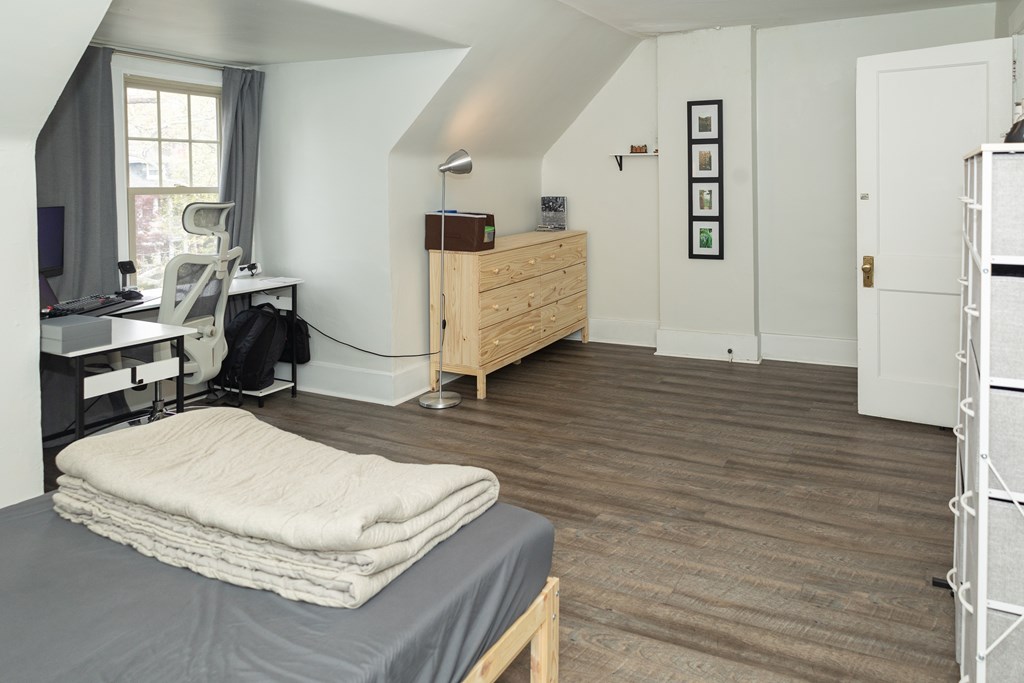 A bedroom with a bed, desk, and chair.