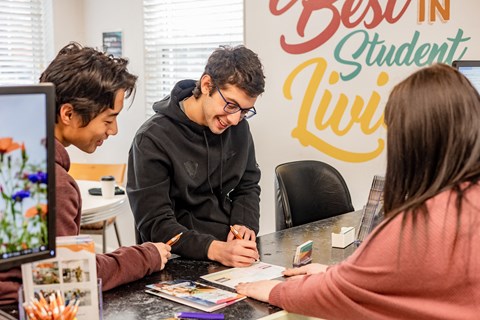 a man and a woman sitting at a table with a piece of paper in front of them at University Commons Apartments, Oakland, Pittsburgh