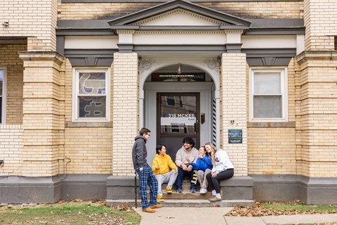 a group of people sitting on the steps of a building at University Commons Apartments, Oakland, Pittsburgh