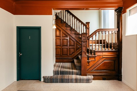 A wooden staircase with a green door on the left.