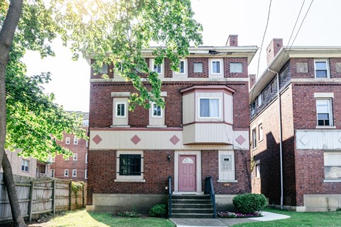 A red brick house with a pink door and a small porch.