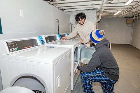 two people installing a washing machine in a laundromat at University Commons Apartments, Oakland, Pittsburgh