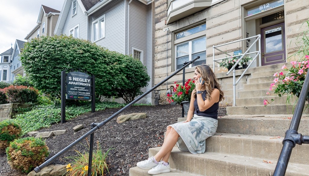 a woman sitting on the steps of a building talking on her cell phone