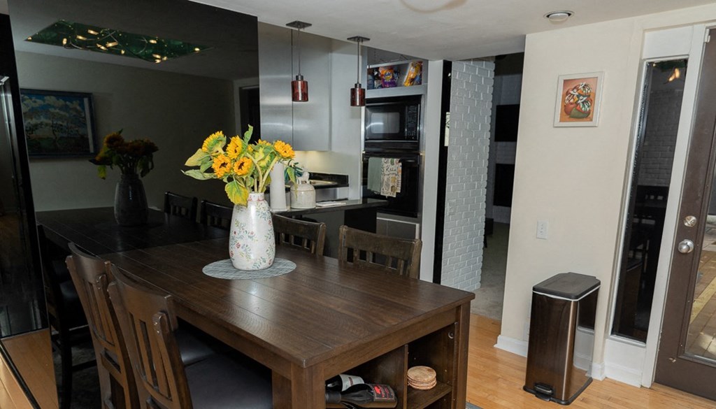 a dining room with a wooden table and chairs and a vase of flowers on the table