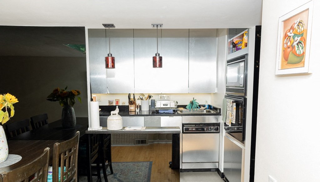 a kitchen with white cabinets and a black table with a vase of yellow flowers