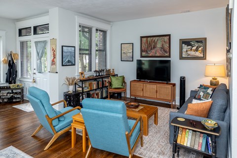A living room with a blue chair and a black couch.