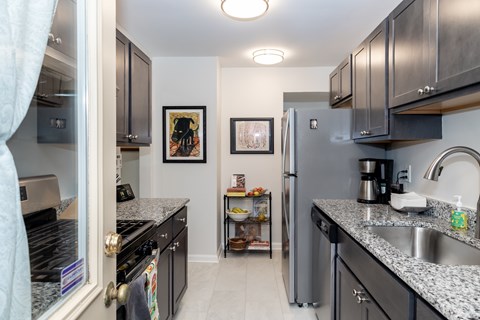 A kitchen with black cabinets and a stainless steel refrigerator.