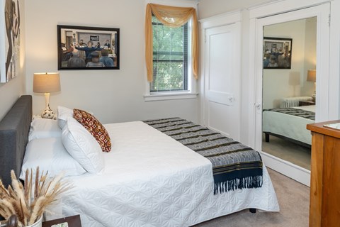 A bedroom with a bed, nightstand, and a mirror.
