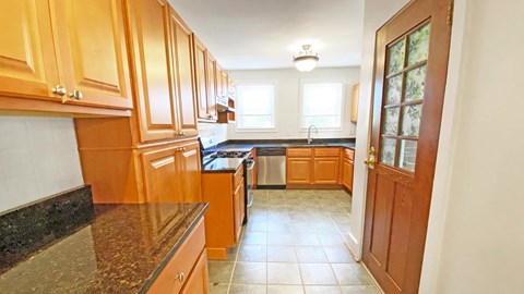 a kitchen with wood cabinets and black countertops