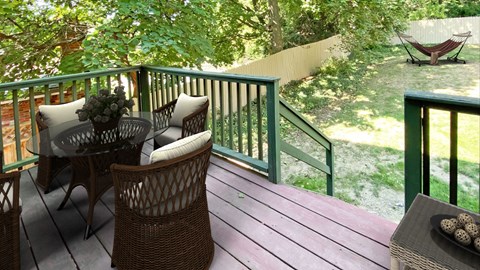 a deck with a table and chairs and a hammock in the background