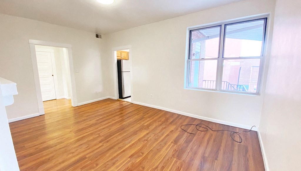 an empty living room with hardwood floors and a large window