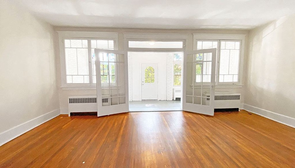 an empty living room with hardwood floors and large windows