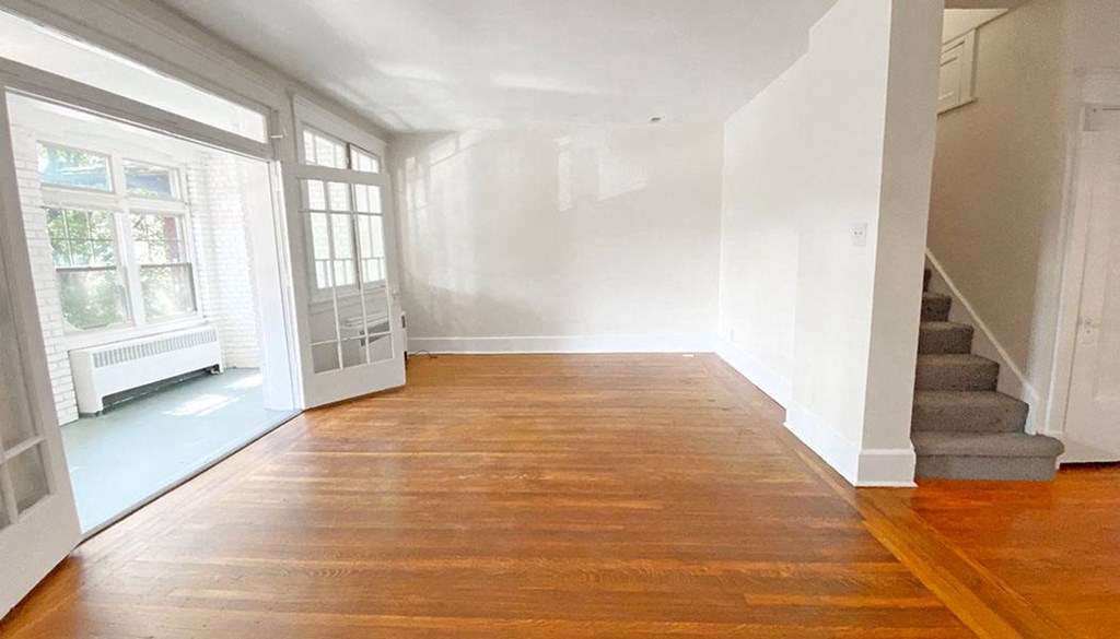 an empty room with white walls and wood floors