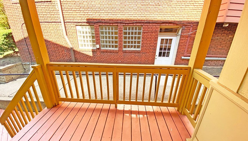 a balcony with a wooden railing and a brick building in the background