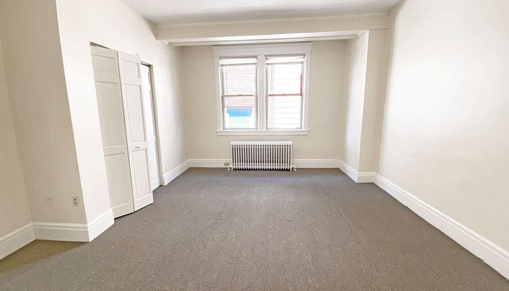 an empty room with a radiator and a window