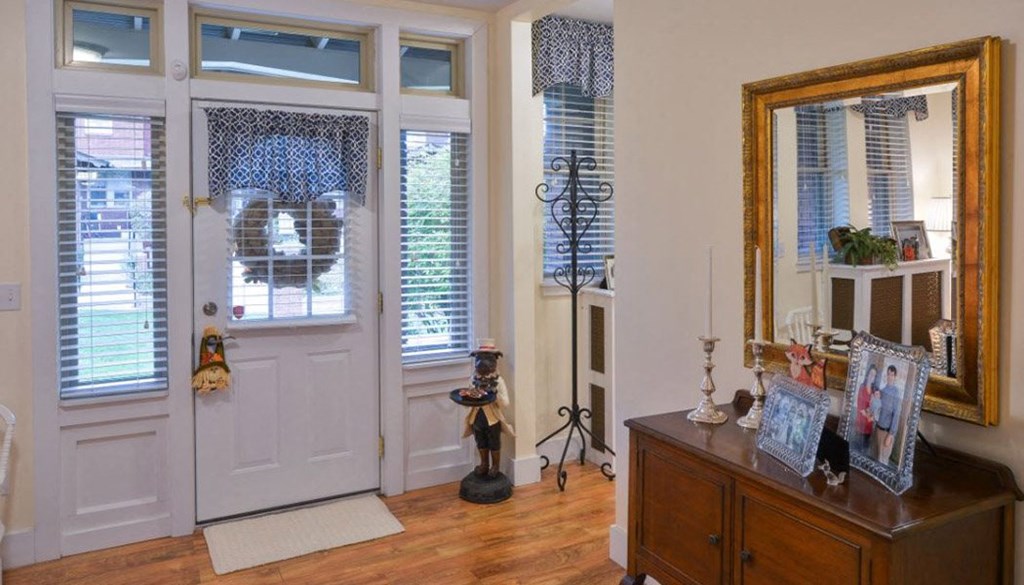 a front door with a large mirror and a dresser in front of it