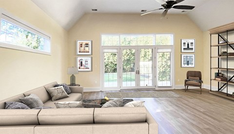 A living room with a beige couch and a ceiling fan.