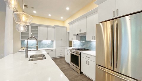 A modern kitchen with a stainless steel refrigerator and white countertops.