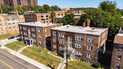an aerial view of a brick building with two chimneys and a grassy area in front