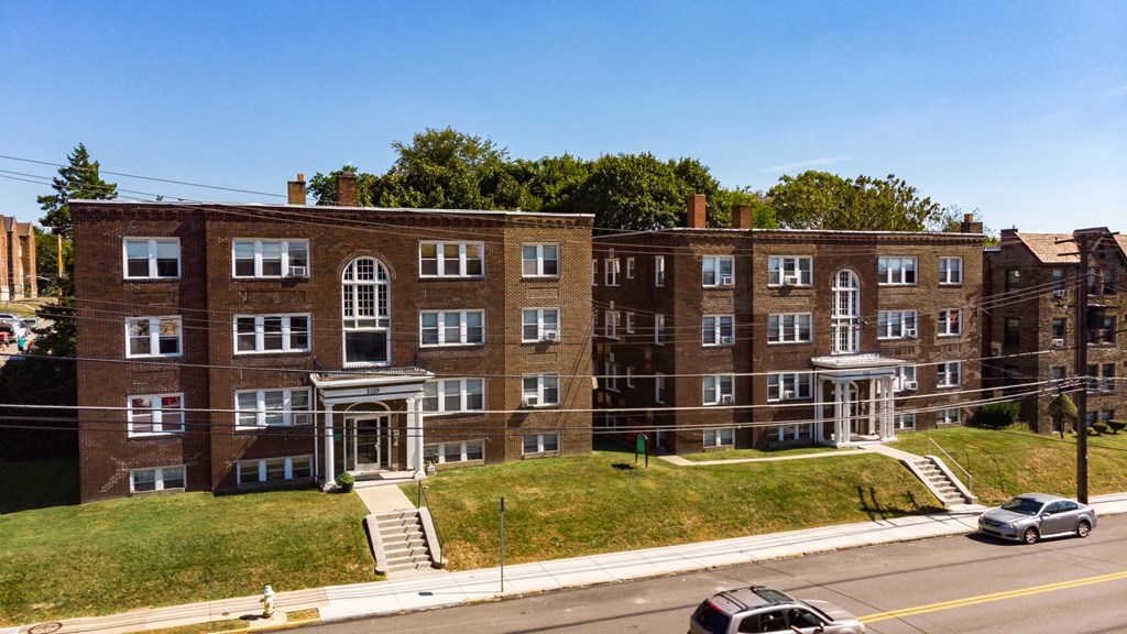 a brick apartment building on a grassy hill with a blue sky in the background