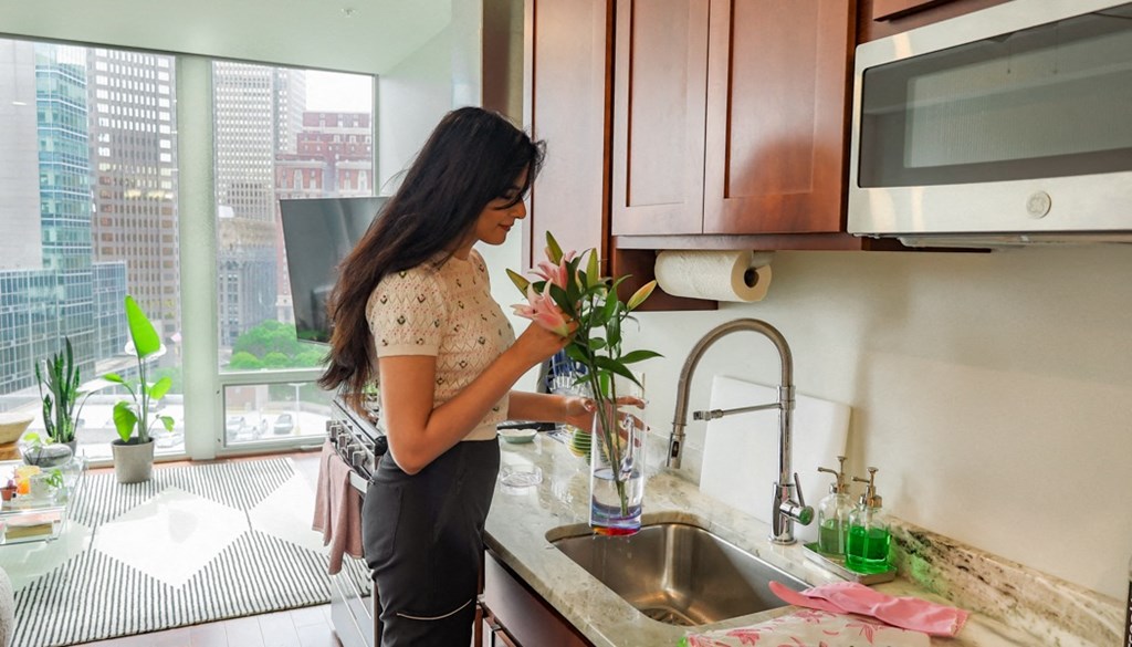a woman in a kitchen arranging a vase of flowers at The Washington at Chatham, Pittsburgh, PA