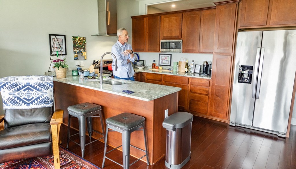 a man stands at a kitchen counter with a sink and three stools at The Washington at Chatham, Pittsburgh, PA 15219