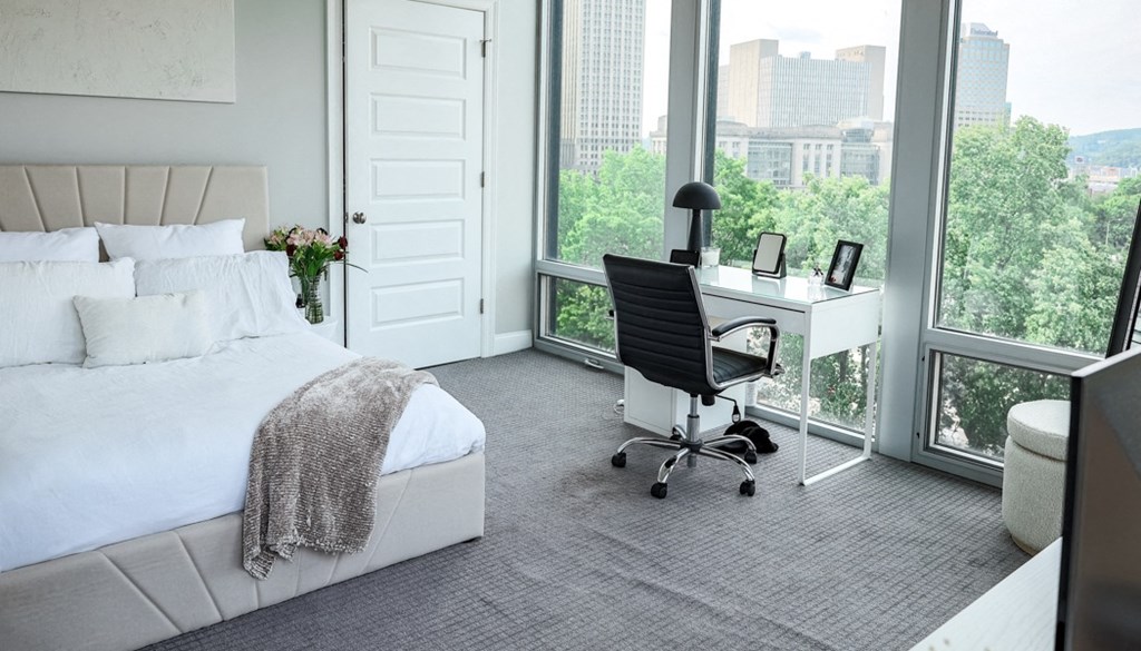 a bedroom with a bed and a desk in front of a window at The Washington at Chatham, Pittsburgh Pennsylvania