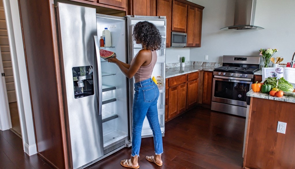 a woman standing in a kitchen looking in a refrigerator at The Washington at Chatham, Pittsburgh