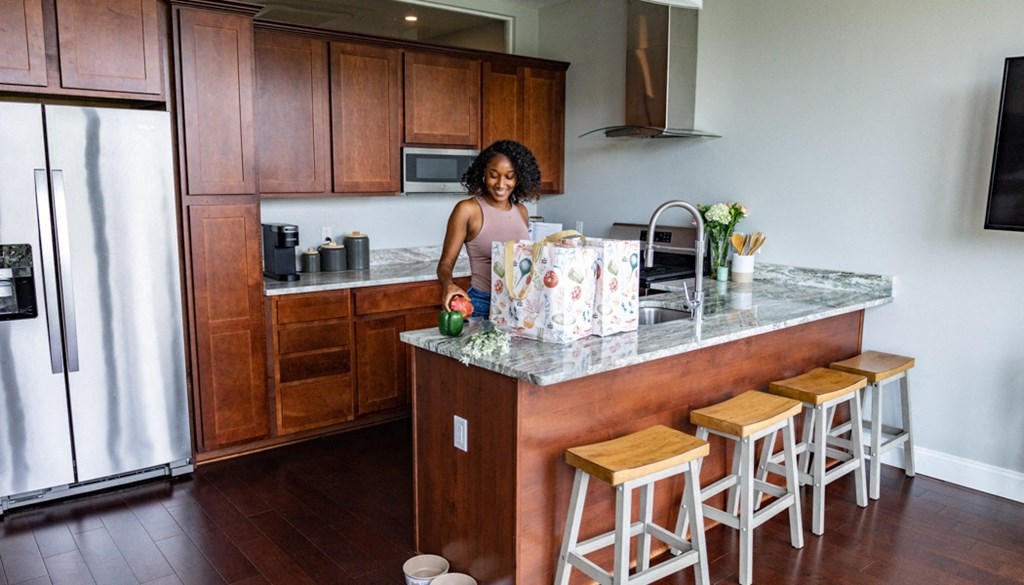 a woman standing at a kitchen counter with a christmas present at The Washington at Chatham, Pittsburgh Pennsylvania