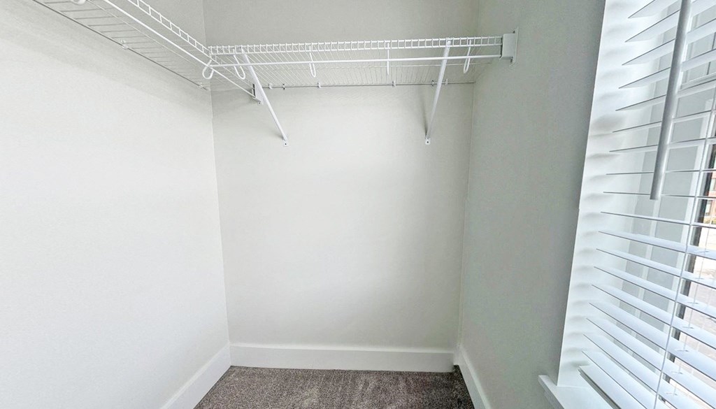 an empty closet in a home with white walls and a white rack on the ceiling