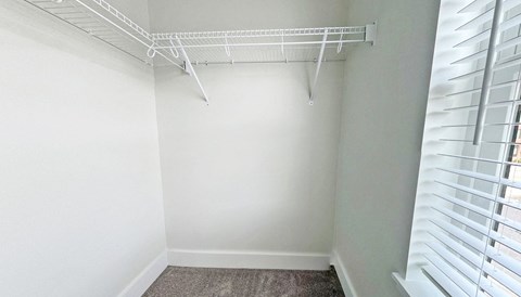 an empty closet in a home with white walls and a white rack on the ceiling