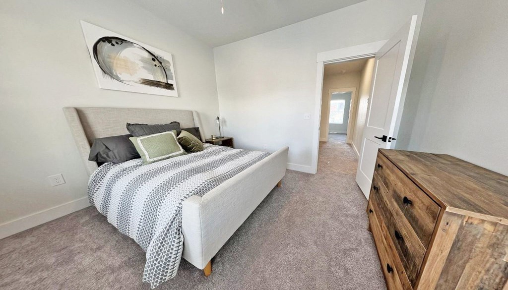 a bedroom with a bed and a wooden dresser