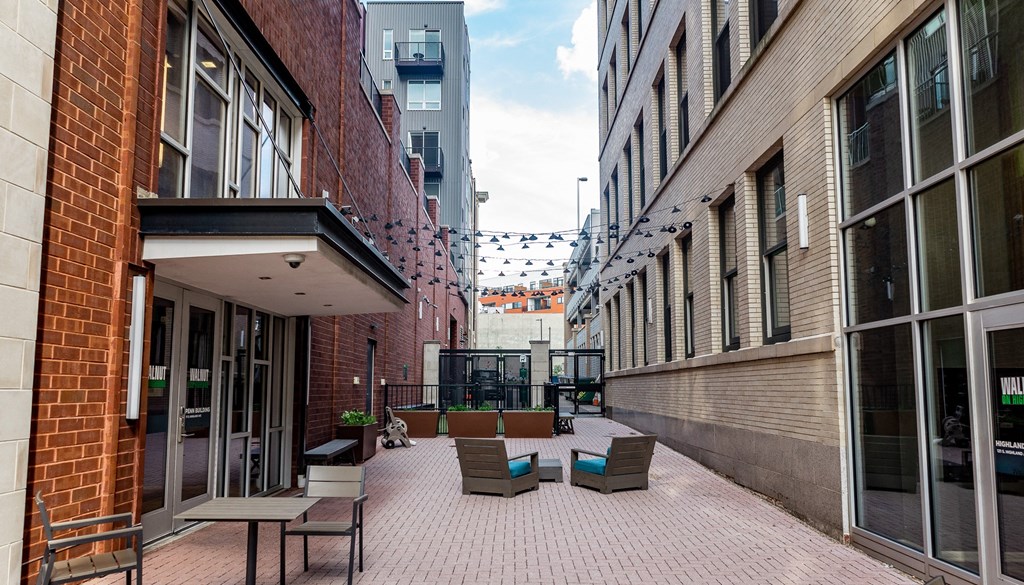 a courtyard with chairs and tables in front of a brick building at Walnut on Highland, Pittsburgh, PA