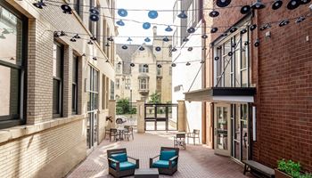 a courtyard with blue chairs and a red brick building in the background