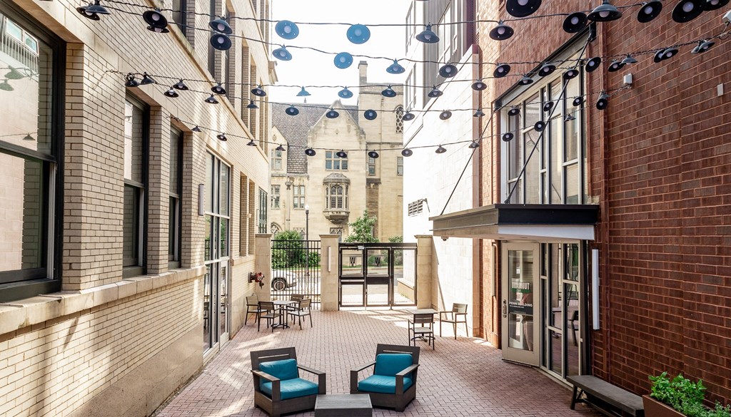 a courtyard with blue chairs and a red brick building in the background at Walnut on Highland, Pittsburgh, PA
