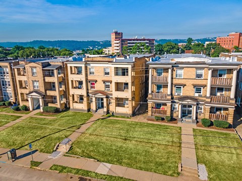 an aerial view of a row of apartment buildings with a grassy area in front of them at University Commons Apartments, Oakland, Pittsburgh