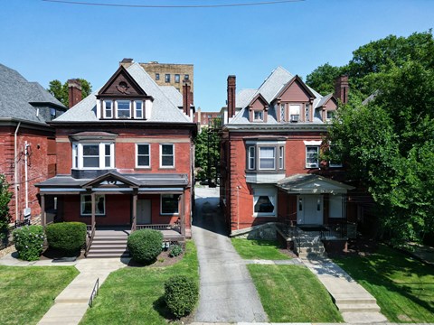 Two red brick houses with white trim and windows.