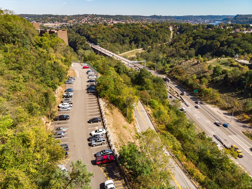 A parking lot with cars is situated on a hillside at Walnut Towers at Frick Park, Pittsburgh, PA
