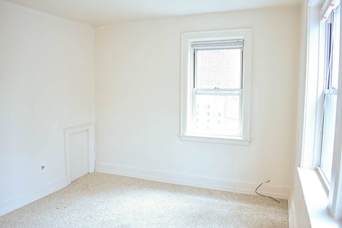 A white room with a window and carpeted floor.