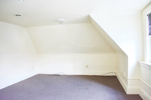 A room with a purple carpet and a window on the right side.