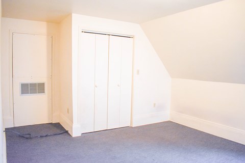 A room with a white door and a grey carpet.