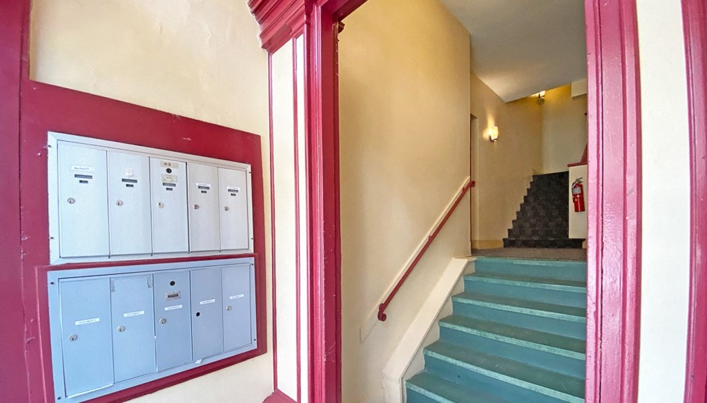 a staircase in a building with mailboxes and a window with a red curtain