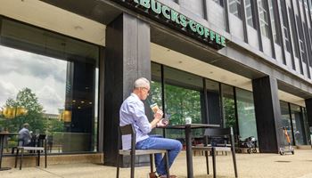 a man sitting in a chair outside a coffee shop at The Washington at Chatham, Pittsburgh Pennsylvania