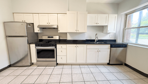A kitchen with white cabinets and black countertops.