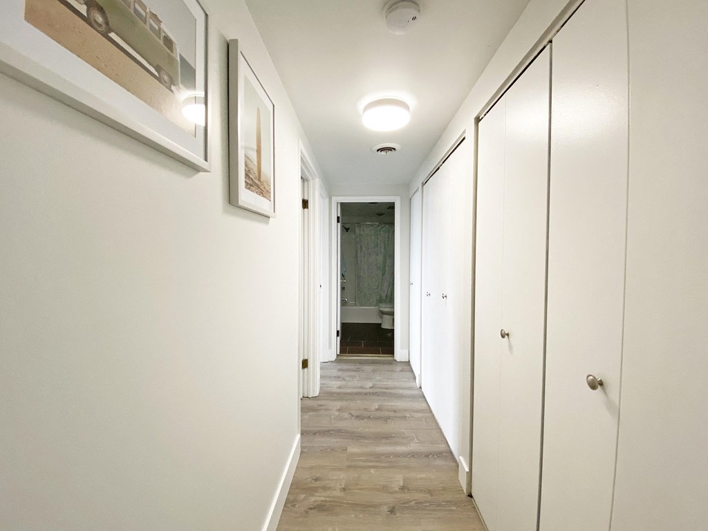 A long hallway with white walls and wood flooring at Walnut Towers at Frick Park, Pittsburgh, Pennsylvania